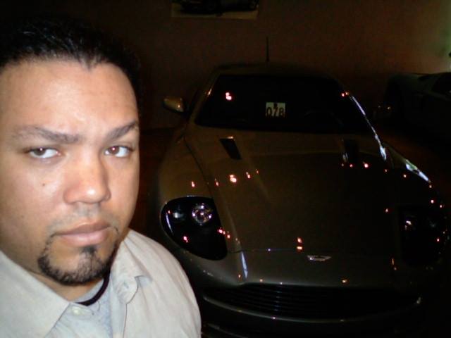 Mervin posing beside a silver sports car