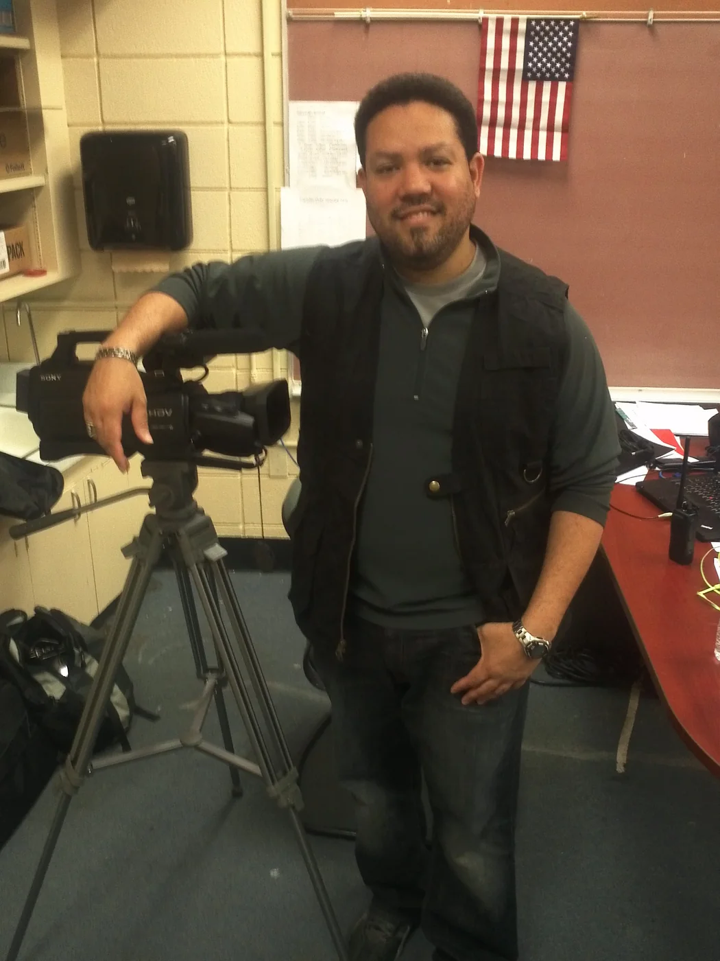 Mervin smiling beside a professional video camera