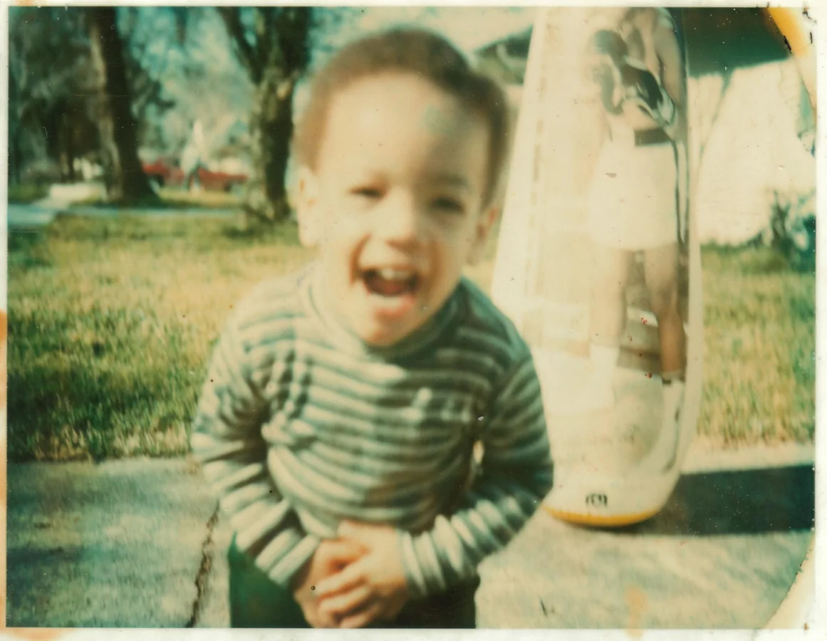 A childhood photograph of Mervin laughing outdoors