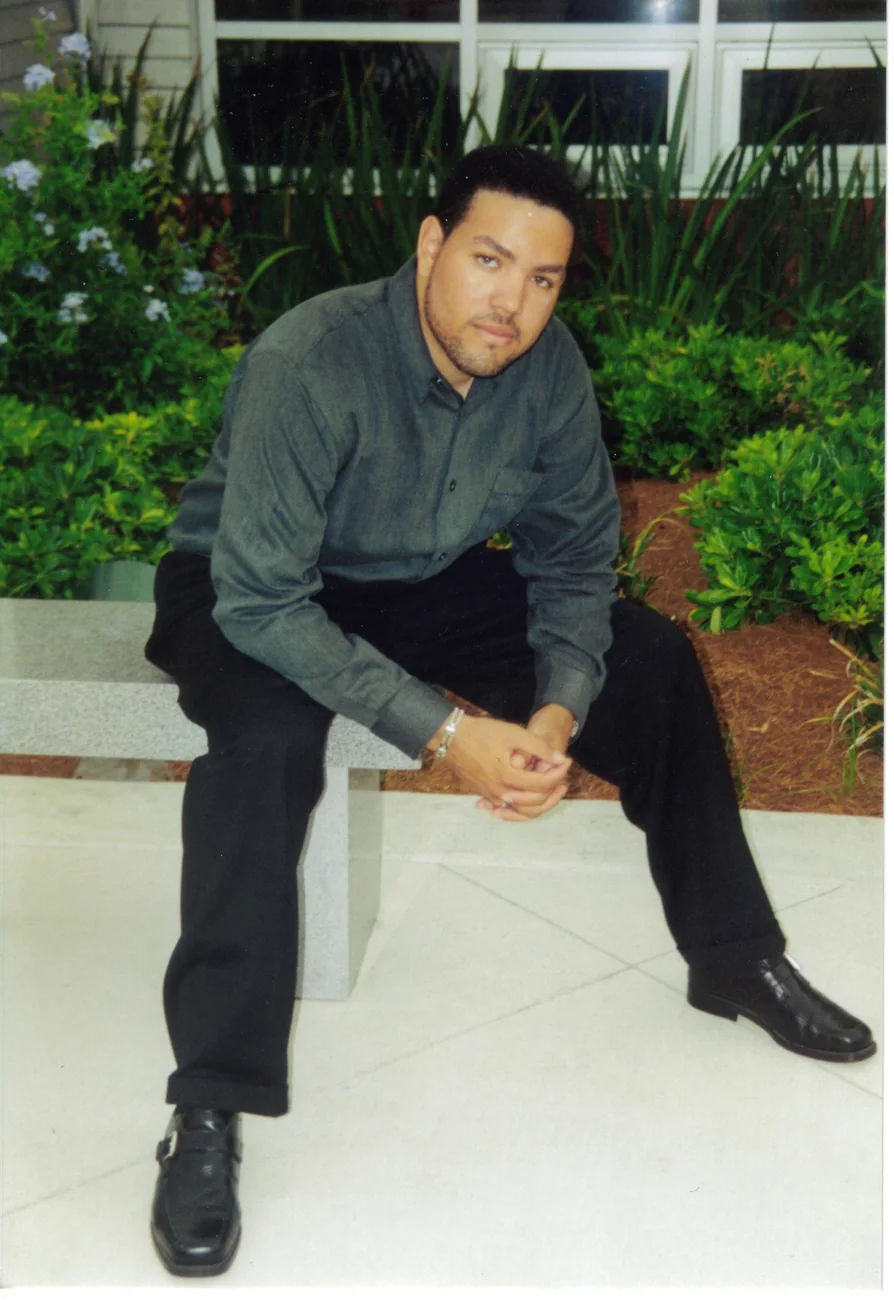 A younger Mervin seated outdoors in a dress shirt